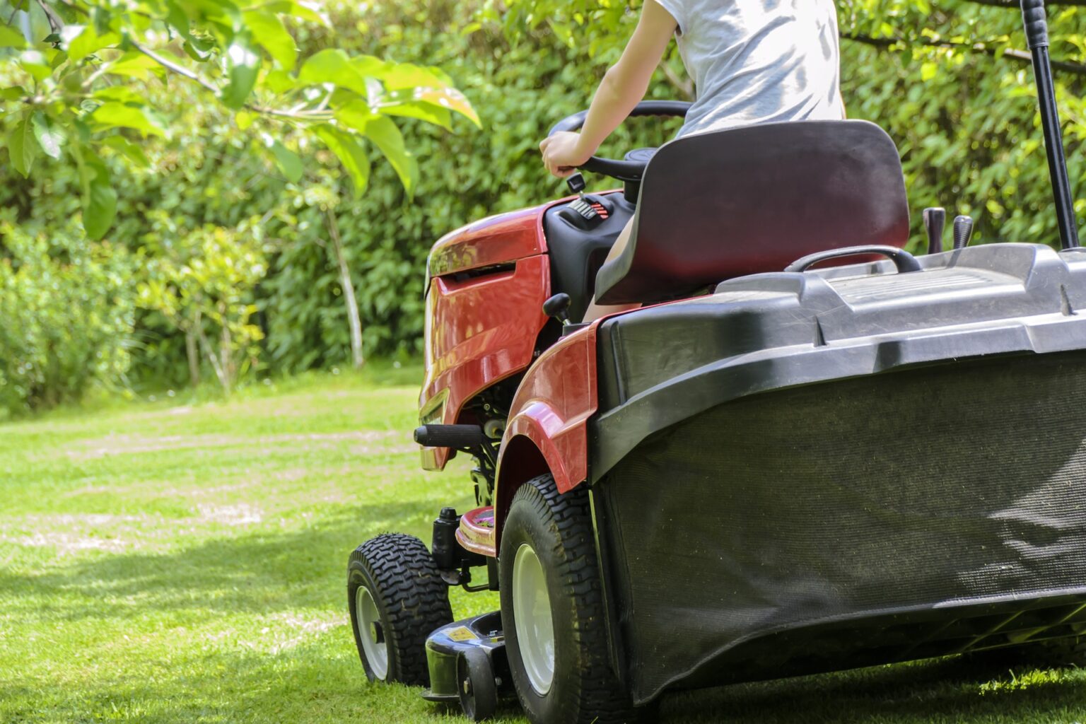 homme entrain de tondre la pelouse avec un tracteur tondeuse